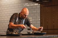 Un hombre en una cocina preparando comida en tazones. en Sofitel Adelaide, en Adelaida