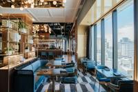 un restaurante con sillas azules, mesas y ventanas en Sofitel Adelaide, en Adelaida