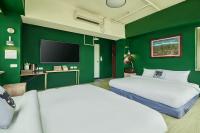 a green room with two beds and a flat screen tv at 安蘭居旅店 An Lan Jie Hotel in Chiayi City