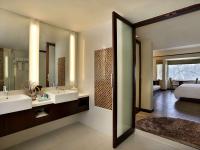 a bathroom with two sinks and a bedroom at Novotel Lombok Resort & Villas in Kuta Lombok