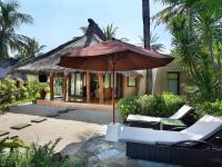 a patio with an umbrella and chairs and a house at Novotel Lombok Resort & Villas in Kuta Lombok