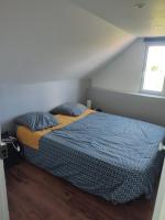 a bedroom with a bed with a blue comforter and a window at La maison fleurie 2 in Sainte-Geneviève-lès-Gasny