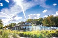a house on a hill with the sun in the sky at Weissenhaus Private Nature Luxury Resort in Weißenhaus