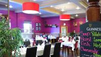 a restaurant with white tables and chairs and purple walls at Great National Hotel Ballina in Ballina