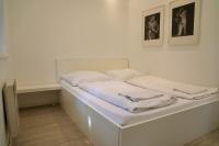 a white bed in a room with two pictures on the wall at Storchencamp Gästehaus Purbach in Purbach am Neusiedlersee