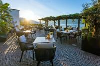 un ristorante con tavoli e sedie e l'oceano di Parkhotel Brenscino Brissago a Brissago
