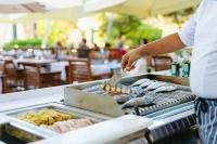 a man is cooking food on a grill at UNAHOTELS Club Hotel Ancora in Stintino
