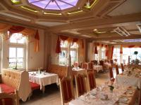 Un restaurante con mesas y sillas blancas y ventanas. en Hotel Zum weißen Stein, en Kirchen