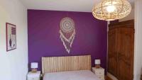 a bedroom with a purple wall with a bed and a chandelier at -Moulin de Solaure- in Pont-de-Quart