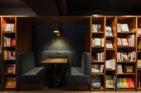a library with two chairs and a table and bookshelves at OLAH Poshtel - Taichung Station in Taichung