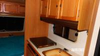 a kitchen with a sink and wooden cabinets at Une pause... Quelque part in Le Torp-Mesnil