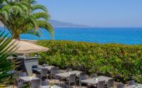 a restaurant with tables and chairs and the ocean at Best Western Premier Hotel Prince de Galles in Menton