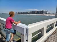 a woman looking over a fence at the beach at Appartement Blankenberge Zeedijk aan de Pier in Blankenberge