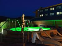 a woman in a bathing suit standing next to a swimming pool at Hotel Vitality in Vendryně