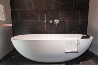 a white bath tub in a bathroom with black tiles at MAISON de la Bonne Vie in Thérondels