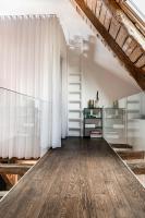 an attic room with a wooden floor and white curtains at MAISON de la Bonne Vie in Thérondels