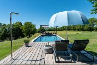 a deck with two chairs and an umbrella next to a pool at MAISON de la Bonne Vie in Thérondels