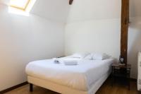 a bedroom with a bed with white sheets and a window at Cacatoès in Saint-Aignan