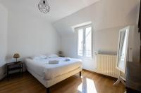 a white bedroom with a bed and two windows at Cacatoès in Saint-Aignan