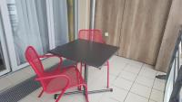 two red chairs and a black table in a room at Résidence Séniors Domitys Les Hautes Feuilles in Reims