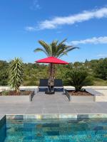 a patio with a red umbrella and chairs and a pool at LES ROCHES DE BAUDISSET in Saint-Paul-en-Forêt