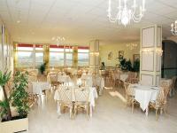 un restaurant avec des tables et des chaises blanches et un lustre dans l&#39;établissement Le Chagny, à Chagny