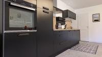 a kitchen with black cabinets and a stove top oven at Le petit Moulin de la Motte in Bellenot-sous-Pouilly