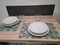 a table with two white plates and glasses on it at Résidence Océane Appartement Nature in Albi