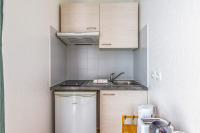 a small kitchen with wooden cabinets and a sink at Nice and cozy studio with balcony - La Rochelle - Welkeys in La Rochelle