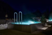 a pool with blue lights in the snow at night at Berghaus Schröcken - Hotel Apartments Spa in Schröcken