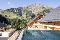 a house with a swimming pool in front of a mountain at Berghaus Schröcken - Hotel Apartments Spa in Schröcken