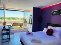 a bedroom with a bed and a table and a balcony at STUDIO CAMP NATURISTE VUE MER, le Gilyves cocooning in Cap d&#39;Agde