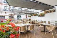 Un restaurante con mesas, sillas y flores. en Neptuno Hotel & SPA 4 Sup, en Calella