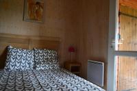 a bedroom with a bed with a wooden wall at Beautiful lake view 3 bedroom chalet. in Saint-Manvieu-Bocage