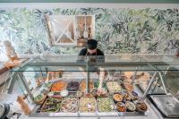 a man standing behind a display case of food at Monastère des Augustines in Quebec City