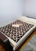 a bed with a brown and white blanket on it at Apartman Elena in Vrnjačka Banja