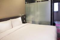 a bedroom with a white bed and a glass wall at Capital Hotel SongShan in Taipei