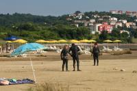 a group of people standing on a beach with umbrellas at Apartments with a parking space Zupanje, Krk - 5307 in Županje