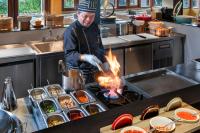 a man cooking food on a stove in a kitchen at Grand Mercure Khao Lak Bangsak in Khao Lak
