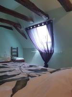 a bedroom with a bed with a purple curtain at Maison Marilene in Ajat
