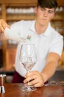 un hombre está vertiendo vino en una copa de vino en Metzenhof, en Kronstorf