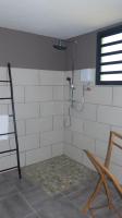 a white tiled bathroom with a shower in a room at Bois de Santal Chambre d&#39;hôtes in Saint-Pierre