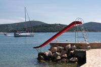 a red slide in the water with a boat at Apartments by the sea Jezera, Murter - 5123 in Jezera