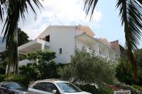 Una casa blanca con autos estacionados frente a ella. en Apartments with a parking space Makarska - 6636, en Makarska