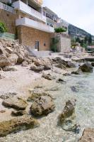 a beach with rocks in front of a building at Apartments by the sea Pisak, Omis - 1018 in Pisak