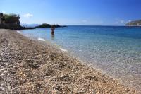 a person standing in the water on a rocky beach at Apartments and rooms by the sea Komiza, Vis - 2431 in Komiža