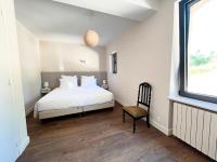 a bedroom with a bed and a window and a chair at Bienvenue au Mas du Roulier, villa provençale avec vue hypnotique sur la chaine des Puys in Thiers