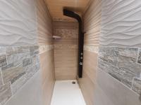 a walk in shower in a bathroom with stone walls at LE GALOPIN Etaples le Touquet in Étaples