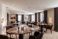 Un restaurante con mesas, sillas y ventanas. en Auberge de Clochemerle - Spa & Restaurant gastronomique étoilé, en Vaux-en-Beaujolais