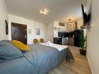 a bedroom with a large bed and a kitchen at LES PIEDS DANS L’EAU - MORET CENTRE in Moret-sur-Loing
